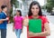 Happy latin female student in red shirt showing thumb