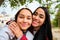 Happy Latin lesbian couple hugging taking a selfie at street.