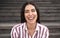 Happy Latin woman smiling into the camera sitting on urban stairs