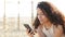 Happy latin woman using smart phone on the beach