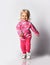 Happy laughing baby kid girl in pink warm fleece clothing with heart print pattern runs towards camera