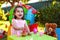 Happy laughing baby toddler girl in outdoor second birthday party holding candle