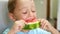 Happy laughing child close-up. A cute little boy sits at a table and eats a juicy watermelon with appetite. Children`s