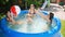 Happy laughing children with mother having fun and playing with inflatable ball in swimming yard. Family summer vacation