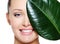 Happy laughing face of woman and large green leaf