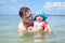 Happy laughing infant baby with dad having fun in the sea. Father teaches daughter to swim and water