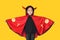 Happy laughing little Asian child girl dressed Halloween costume. Kid in Dracula robe isolated on yellow background