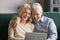 Happy laughing mature husband and wife having fun with laptop