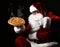 Happy laughing Santa Claus hold big hot steaming original pizza offering pointing finger. New year and Merry Christmas fast food