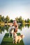 Happy laughing woman have fun with her dogs on pier at lake during sunny day in summer