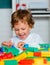 Happy launching toddler playing with building blocks toys at kindergarten. Elementary school and education.