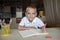 Happy left-handed boy writing in the paper book with his left hand, international left-hander day