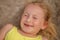 Happy littl girl lies on the sea sand with a seashell on her nose