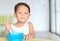Happy little Asian baby boy eating cereal with cornflakes and milk stains around mouth on the table. Children having breakfast at