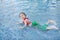 Happy little Asian child girl in a mermaid suit lying poolside with looking camera