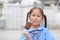 Happy little Asian child girl in school uniform enjoy eating chocolate vanilla ice cream outdoors