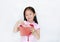 Happy little Asian child girl wearing pink traditional cheongsam dress smiling while receiving Chinese New Year red envelope