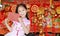 Happy little Asian child girl wearing pink traditional cheongsam dress smiling while receiving red envelope packet on chinese luck