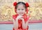 Happy little Asian child girl wearing red cheongsam with greeting gesture celebration for Chinese New Year at chinese temple in