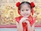 Happy little Asian child girl wearing red cheongsam with greeting gesture celebration for Chinese New Year at chinese temple in
