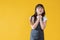 A happy little Asian girl is standing against an isolated yellow background in a cute pose