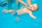 Happy little baby swimming in water pool with help from mothers hands