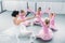 happy little ballerinas and ballet teacher sitting and holding hands