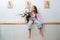 Happy little barefoot girl in oversized sweater sitting on a shelf hugging flower jar