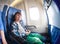 Happy little boy in airplane seat sit by window