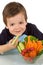 Happy little boy with a bowl of fresh vegetables