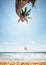 Happy little boy dangles on tropical palm tree swing