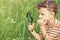 Happy little boy exploring nature with magnifying glass