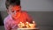 Happy little boy of four sits on the couch looking at the burning candles on the birthday cake, makes a birthday wish