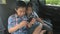 Happy little boy girl wearing seatbelts hold smartphone in car