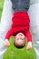 Happy little boy hanging upside down on meadow