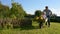 Happy little boy having fun in a wheelbarrow pushing by dad in domestic garden