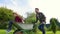 Happy little boy having fun in a wheelbarrow pushing by dad in domestic garden on warm sunny day.