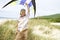 Happy Little Boy Holding Kite Above Head On Beach