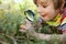 Happy little boy looking through magnifying glass