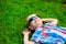 Happy little boy lying down resting on the green grass