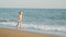 A happy little boy runs along the beach at sunset in the waves of the warm sea