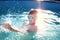 Happy little boy splashing in swimming pool