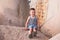 Happy little boy in vest sits on breakwater in port