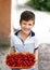 Happy little caucasian boy holding cherry in bowl