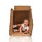 Happy little child baby girl hiding in a cardboard box having fu