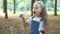 Happy little child girl blowing soap bubbles outside in green park. Outdoor summer activities for children concept