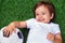 Happy little child laying on a green football field holding soccer ball and smiling. Future football star and little sportsman