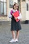 Happy little child in school uniform hold library books in schoolyard outdoors, knowledge day