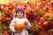 Happy little cute girl carrying, holding, collecting orange pumpkin. smiling kid harvesting in autumn on red maple background.