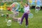 Happy little girl is catching soapy bubbles